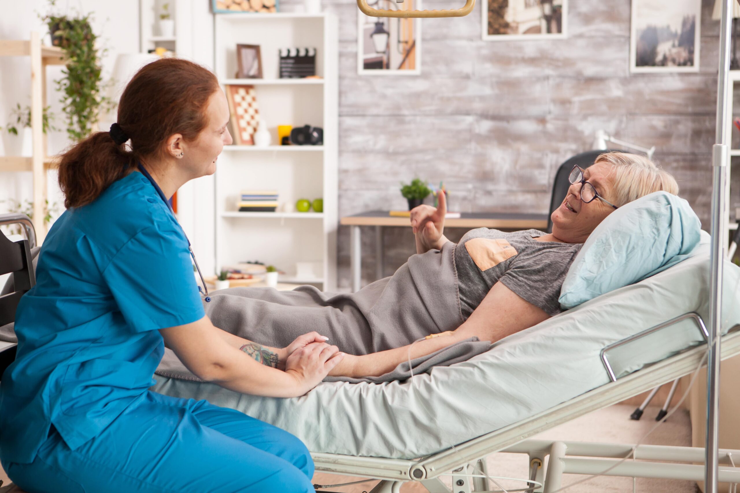 woman laying in a Hospital Bed while having a discussion with a nurse